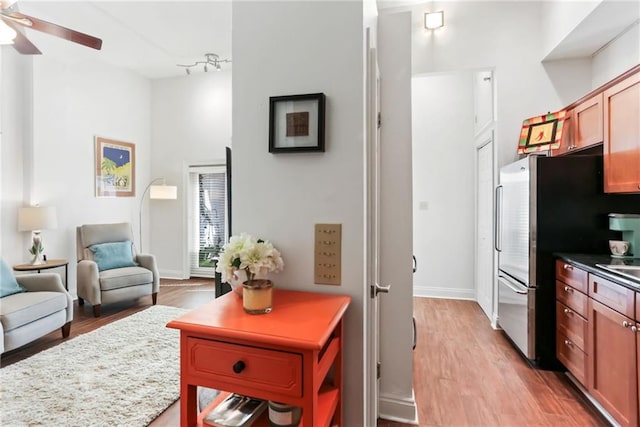 kitchen featuring a ceiling fan, baseboards, open floor plan, light wood-type flooring, and freestanding refrigerator