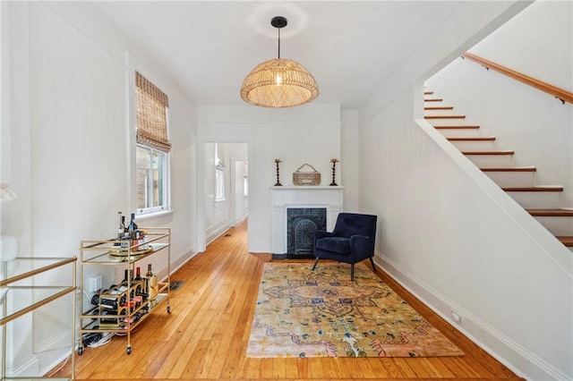 living area with a fireplace with flush hearth, stairway, baseboards, and hardwood / wood-style flooring