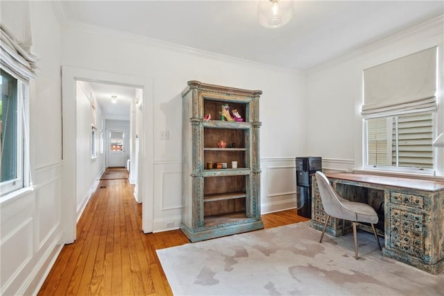 home office featuring ornamental molding, a decorative wall, and wood finished floors