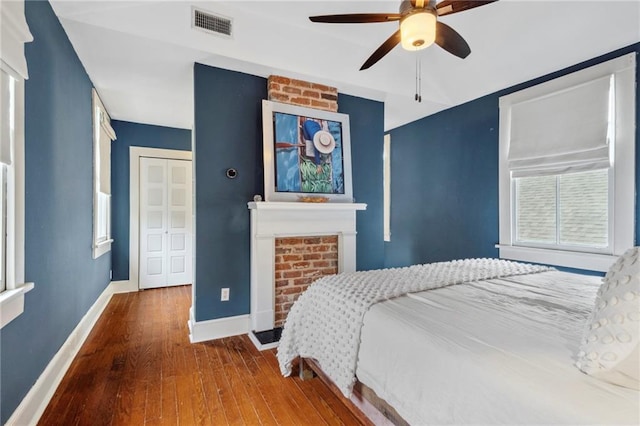 bedroom with a closet, visible vents, ceiling fan, wood finished floors, and baseboards