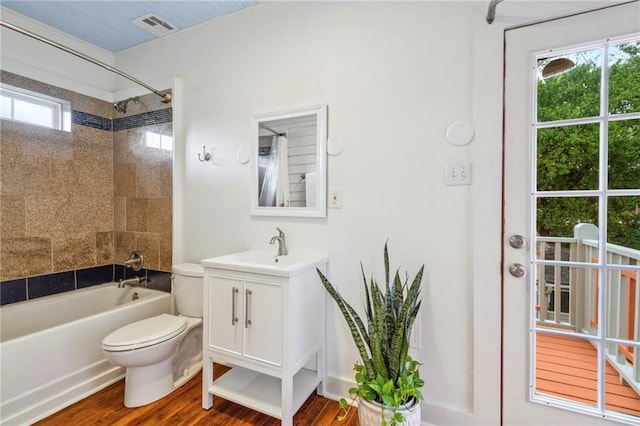 bathroom with toilet, wood finished floors, visible vents, vanity, and shower / bathing tub combination