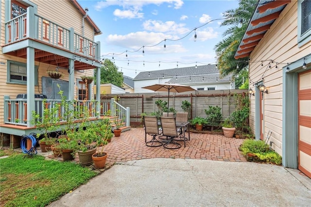 view of patio featuring a balcony, fence, and outdoor dining space