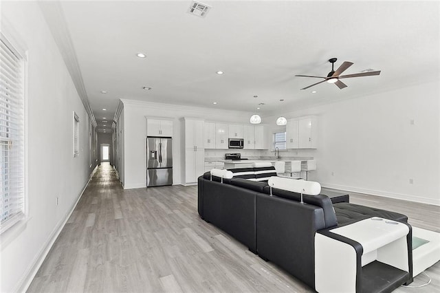 living room with light wood-style floors, visible vents, crown molding, and recessed lighting