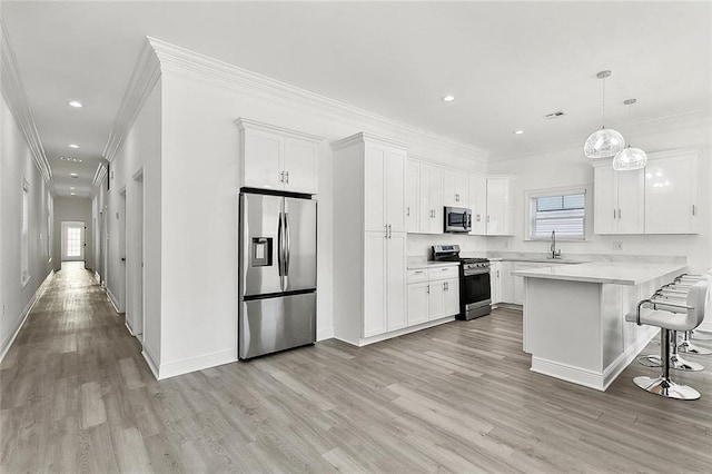 kitchen featuring stainless steel appliances, a breakfast bar, a peninsula, a sink, and white cabinetry