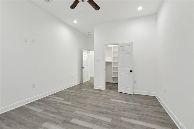 3507 Danneel St, New Orleans, LA 70115 - unfurnished bedroom with wood finished floors, a walk in closet, baseboards, recessed lighting, and a towering ceiling