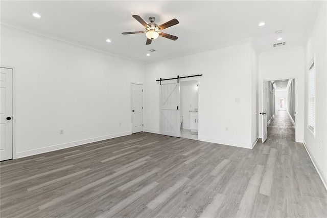 unfurnished bedroom with ornamental molding, wood finished floors, visible vents, and a barn door