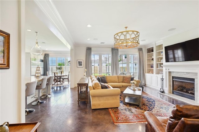 living area featuring a high end fireplace, built in shelves, crown molding, recessed lighting, and an inviting chandelier