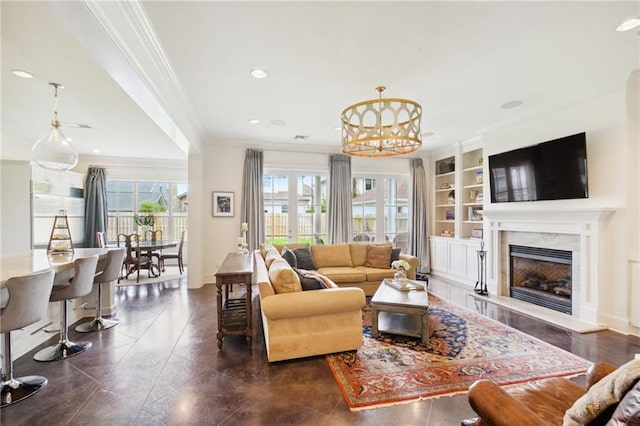 living area with a high end fireplace, built in features, ornamental molding, recessed lighting, and a notable chandelier