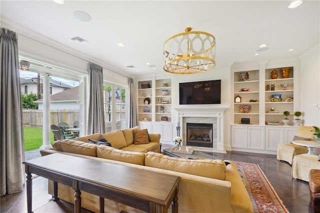 living area featuring built in shelves, visible vents, a fireplace, ornamental molding, and a chandelier