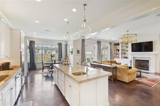 kitchen with crown molding, decorative light fixtures, a fireplace, and a sink