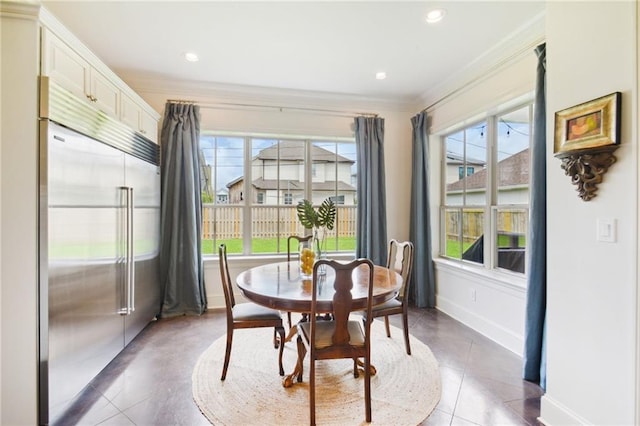 tiled dining area with crown molding, a healthy amount of sunlight, and baseboards