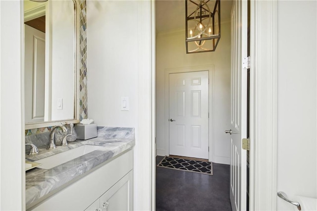 laundry area with ornamental molding, an inviting chandelier, and a sink