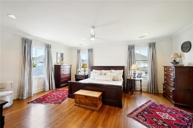 bedroom with baseboards, a ceiling fan, wood finished floors, and crown molding