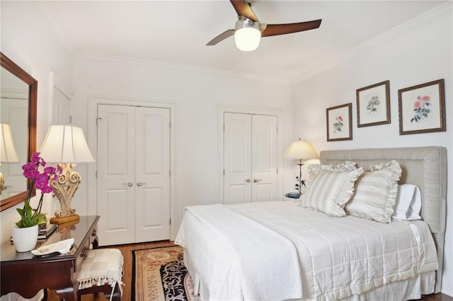 bedroom featuring wood finished floors, two closets, a ceiling fan, and ornamental molding