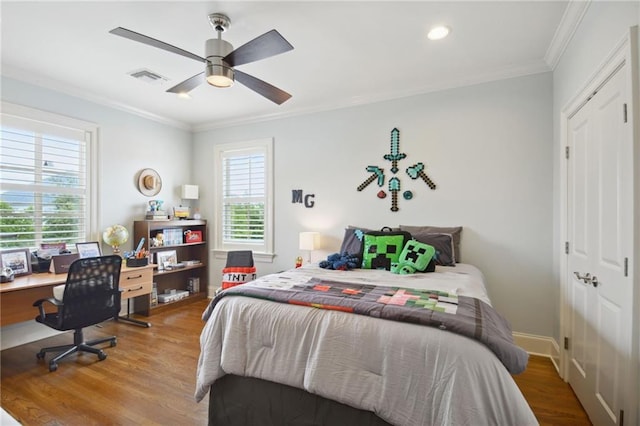 bedroom featuring visible vents, crown molding, baseboards, and wood finished floors