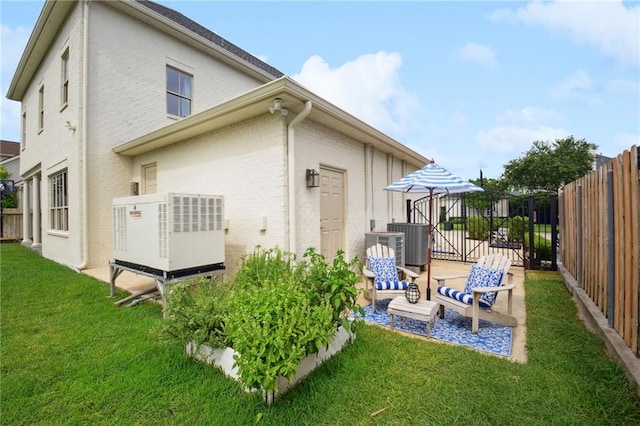 rear view of house with stucco siding, a lawn, cooling unit, and fence