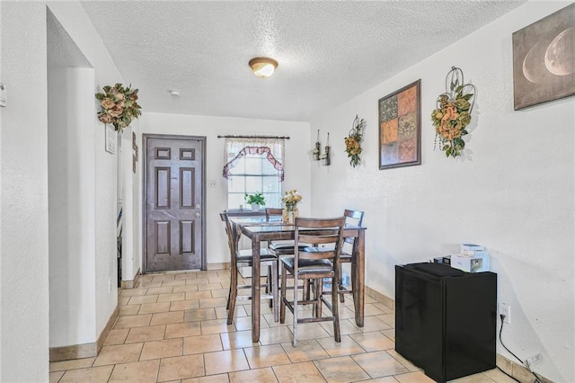 dining space featuring baseboards, a textured ceiling, and a textured wall