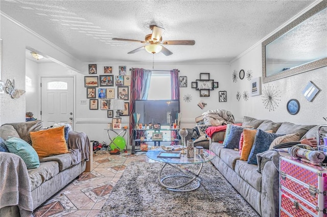 living room with a ceiling fan, a textured wall, tile patterned floors, crown molding, and a textured ceiling