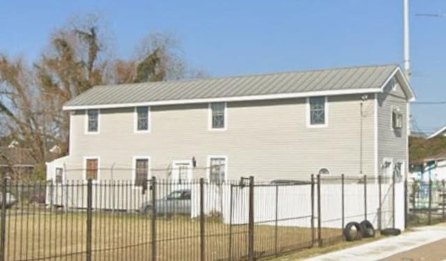 rear view of house with metal roof and fence