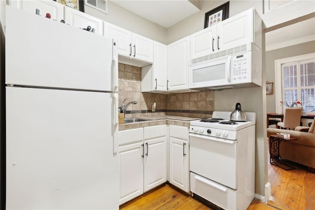 421 Burgundy St Unit 1, New Orleans, LA 70112 - kitchen with white appliances, light wood-style floors, decorative backsplash, white cabinetry, and light countertops
