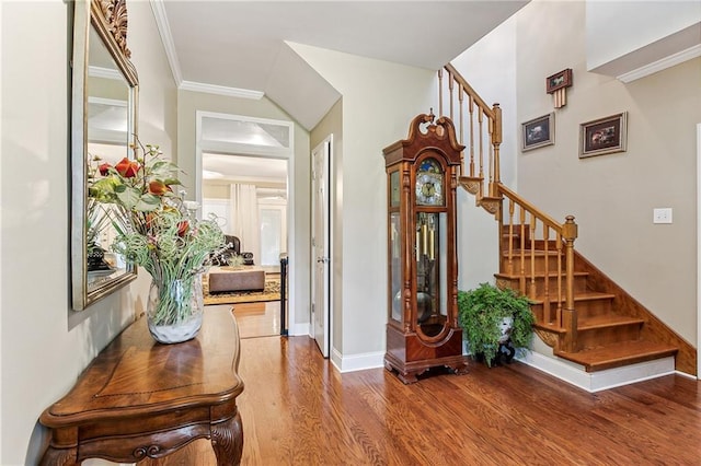 foyer entrance featuring crown molding, stairway, wood finished floors, and baseboards