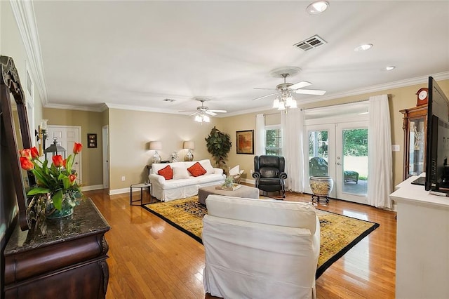 living room featuring visible vents, light wood-style flooring, baseboards, and ornamental molding