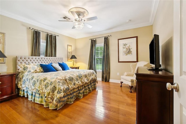 bedroom with crown molding, wood finished floors, visible vents, and baseboards