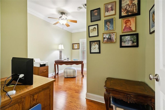 office with baseboards, a ceiling fan, wood finished floors, and crown molding