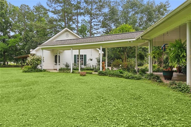 rear view of house featuring a yard and roof with shingles