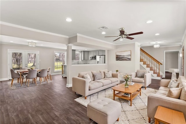 living room featuring crown molding, dark wood-type flooring, visible vents, stairway, and ornate columns