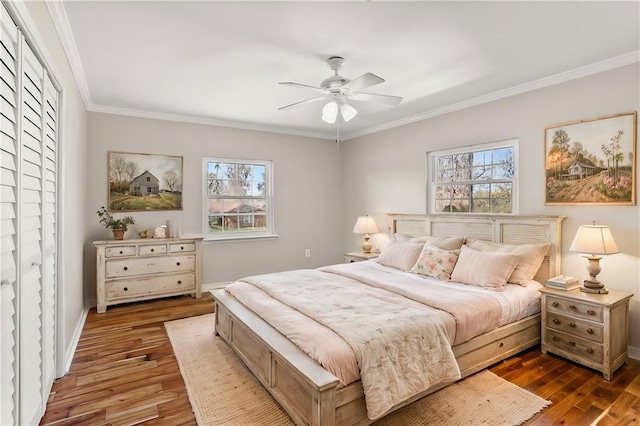 bedroom with crown molding, multiple windows, baseboards, and wood finished floors