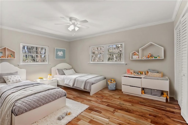 bedroom featuring a ceiling fan, a closet, ornamental molding, and wood finished floors