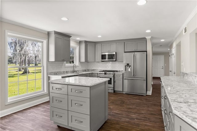 kitchen with gray cabinets, ornamental molding, high end appliances, and decorative backsplash