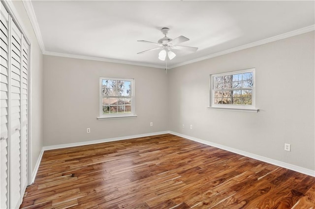 unfurnished room featuring a wealth of natural light, crown molding, baseboards, and wood finished floors