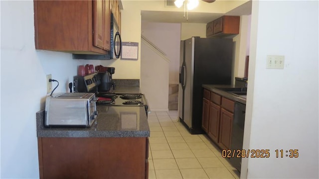 kitchen featuring dark countertops, a toaster, black appliances, and light tile patterned floors