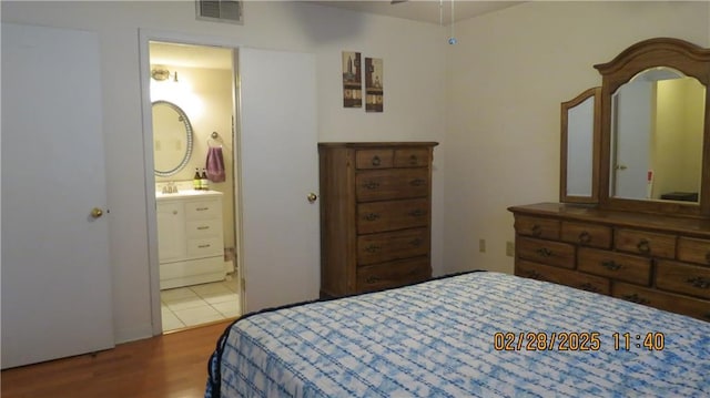 bedroom with visible vents, ensuite bathroom, and wood finished floors