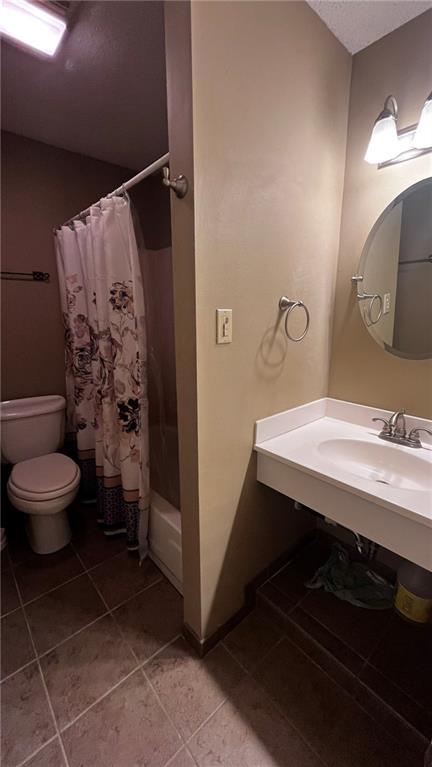 bathroom with a sink, shower / bathtub combination with curtain, toilet, and tile patterned floors