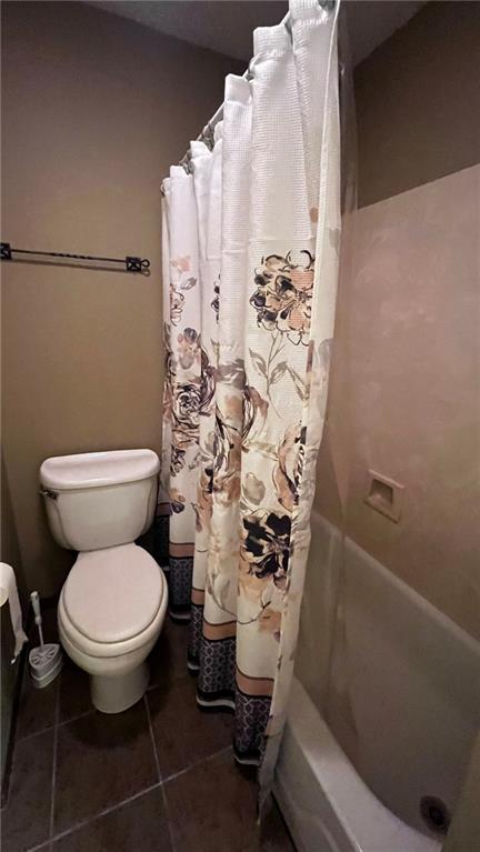 bathroom featuring shower / tub combo, toilet, and tile patterned floors