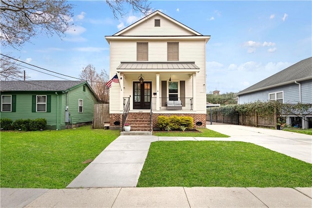 view of front of property featuring covered porch, a standing seam roof, metal roof, fence, and a front lawn