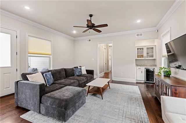 living room with a dry bar, visible vents, wine cooler, dark wood-style flooring, and crown molding