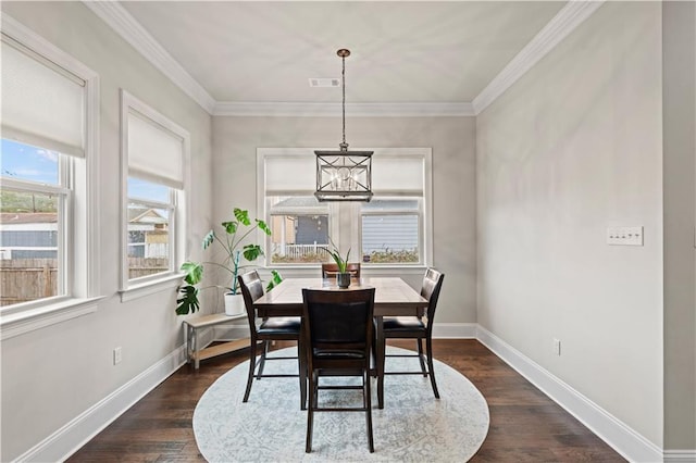 dining space featuring baseboards, visible vents, dark wood-style floors, crown molding, and a chandelier