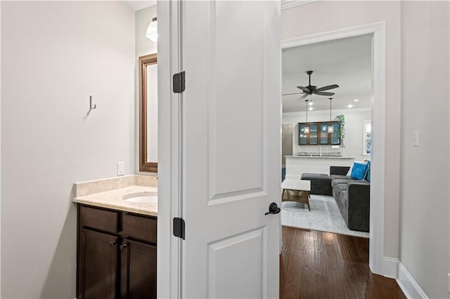 bathroom featuring wood-type flooring, ceiling fan, vanity, and baseboards