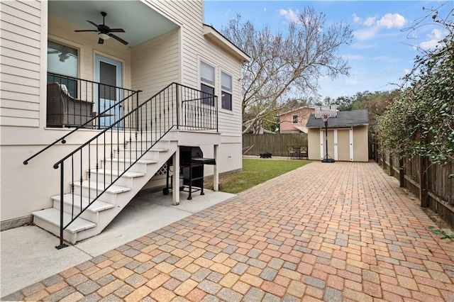 view of patio / terrace featuring a ceiling fan, a fenced backyard, an outdoor structure, and a storage shed