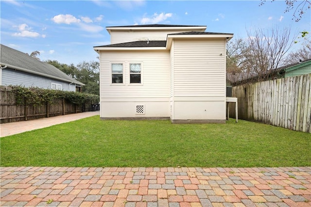 rear view of house with crawl space, a fenced backyard, a lawn, and a patio