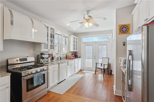 kitchen featuring french doors, light wood-style flooring, appliances with stainless steel finishes, glass insert cabinets, and white cabinets