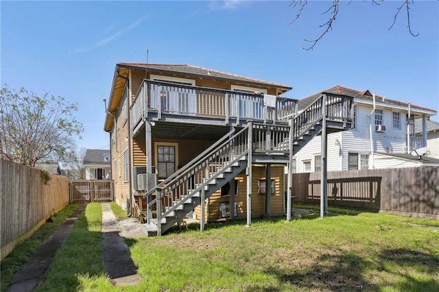 back of house featuring a deck, a fenced backyard, stairs, a lawn, and a gate