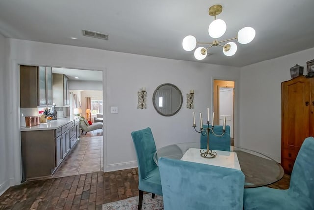 dining room featuring brick floor, visible vents, and baseboards