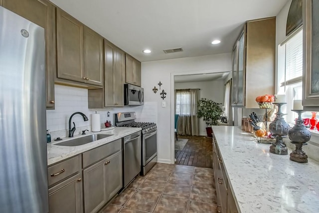 kitchen featuring visible vents, decorative backsplash, dark tile patterned flooring, appliances with stainless steel finishes, and a sink