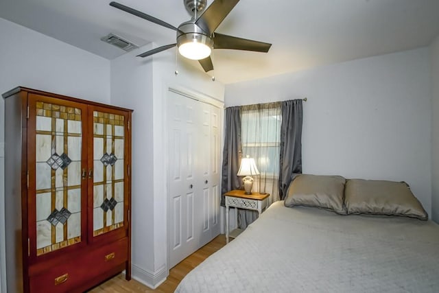 bedroom featuring a ceiling fan, a closet, visible vents, and wood finished floors