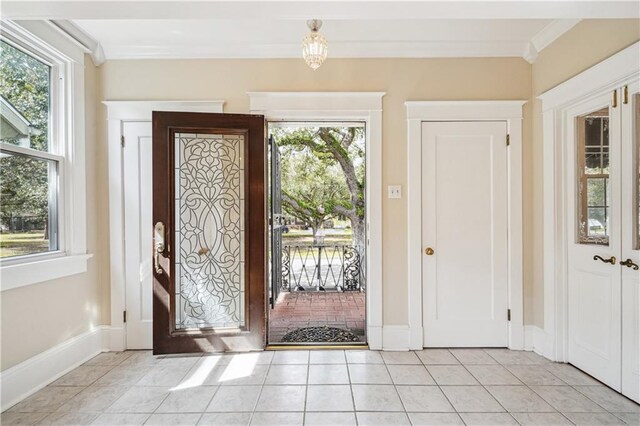 entrance foyer featuring baseboards, plenty of natural light, light tile patterned flooring, and crown molding